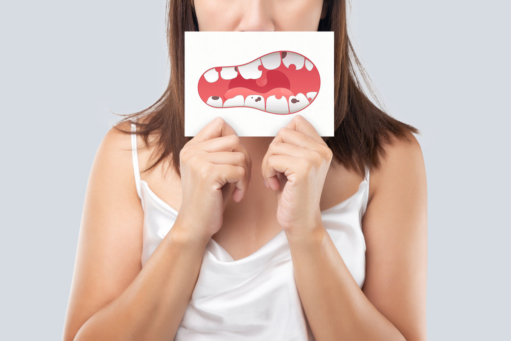 An image of a woman holding a paper that depicts decaying tooths